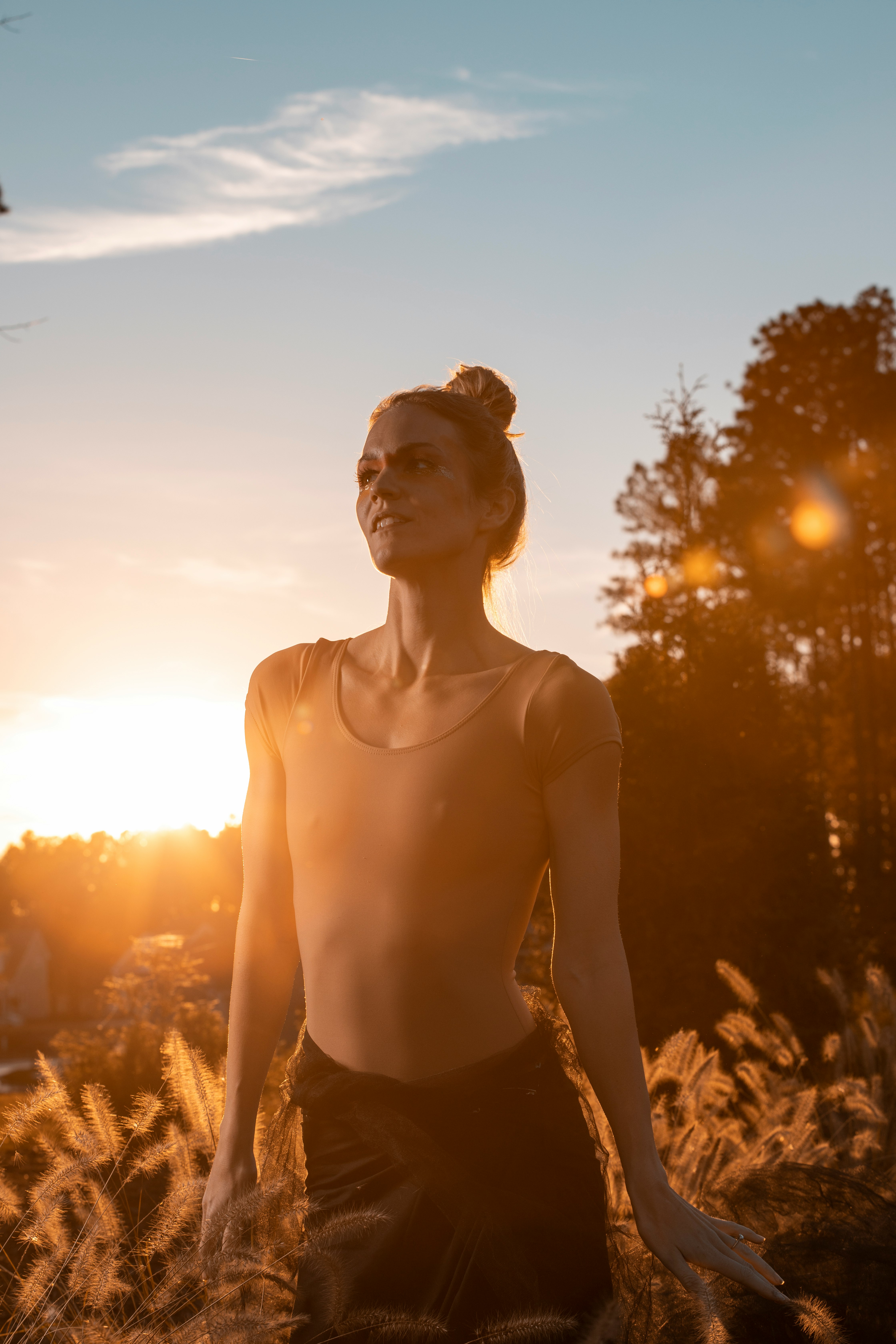 topless woman standing on brown grass field during sunset